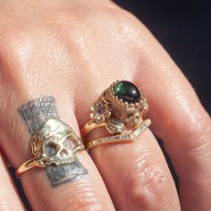 A garden snake wraps around a skull resting in a bed of flowers in an allegory come to life that you can wear on your finger. Named Nozarashi, Japanese for "weather beaten bones" in a twist on traditional memento mori rings. A snake for shedding old ways, flowers for growth, and an open minded skull to live life to the fullest. One of a kind and handmade in solid 14k yellow gold by Nick Potash in his Maui, Hawaii Studio. Unheated green sapphire cabochon brain (1.8ct), violet sapphire flowers, or Aesthetic Vintage Rings, Luxury Antique Black Rings, Weird Engagement Rings, Strange Rings, Garden Snake, Memento Mori Ring, Violet Sapphire, Bed Of Flowers, Unusual Wedding Rings