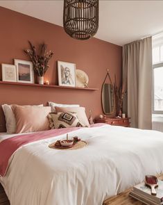 a bed with pink sheets, pillows and pictures on the wall above it in a bedroom