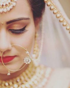 a woman in a bridal outfit with her eyes closed and nose ring on top of her head