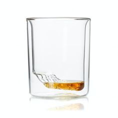 a glass filled with liquid and ice on top of a table next to a white background