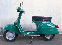 a green scooter parked next to a white wall