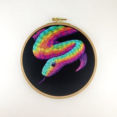 a colorful snake painted in bright colors on a black background with wooden hoop hanging from the wall