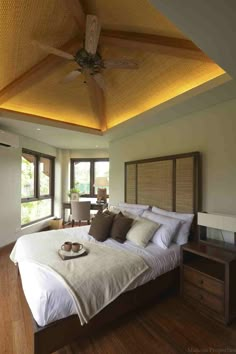 a large bed sitting under a wooden ceiling in a bedroom next to two tables and chairs