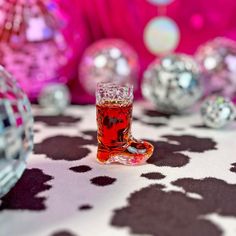 a glass filled with liquid sitting on top of a table next to disco ball decorations