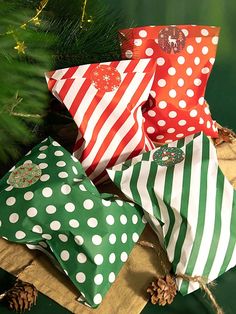 christmas presents wrapped in red and green paper with white polka dots are sitting on a piece of wood