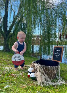 a baby standing in the grass next to a basket with a sign that says when i was born