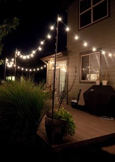 an outdoor patio with lights strung over it and a grill on the deck in front