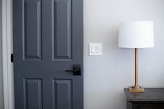 the lamp is on next to the door in the room that's painted gray