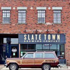 an old station wagon is parked in front of a brick building with the name slate town brewing company on it