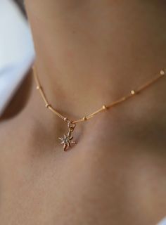 A delicate gold necklace adorned with a star-shaped pendant rests on a woman's neck, highlighting the skin's smooth texture and the soft lighting of the environment. Starburst Necklace, Star Burst, Long Chain Necklace, Shine On, Stylish Jewelry, Star Charms, Gold Filled Chain, Ball Chain, Chain Lengths