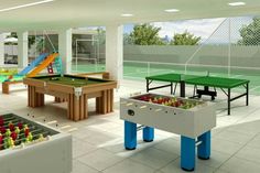 an indoor recreation room with foosball and ping pong tables in the center