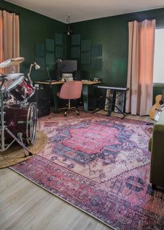 a living room filled with furniture and a drum set on top of a pink rug