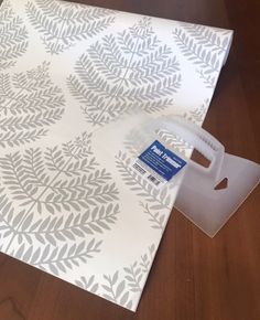 a piece of paper with a white and grey leaf pattern on it next to a plastic bag