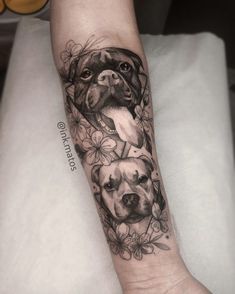 a woman's arm with two dogs on it and flowers around the wrist tattoo