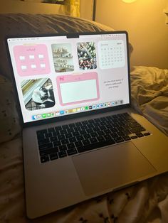 an open laptop computer sitting on top of a bed next to a lamp and pillows