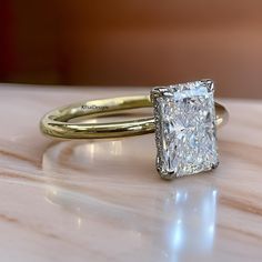 a close up of a diamond ring on a table with a marble surface in the background