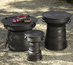 two black metal stools sitting next to each other on top of gravel covered ground