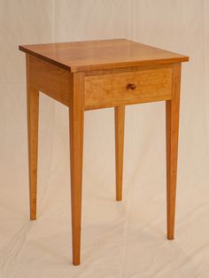 a small wooden table sitting on top of a white sheet