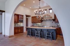 an archway leading into a kitchen with wooden cabinets and counter tops, along with two bar stools