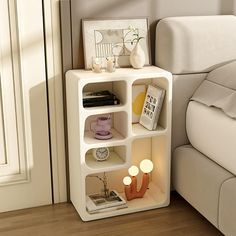 a white shelf sitting next to a bed on top of a hard wood floor covered in furniture