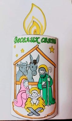 a lit candle with an image of the birth of jesus