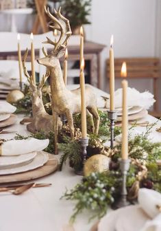 the table is set with candles, plates and deer figurines