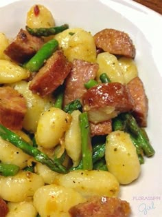 a white plate topped with pasta, asparagus and gnocchi skillet