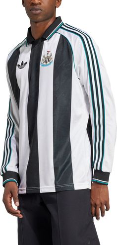 a man wearing a black and white striped shirt with an adidas logo on it