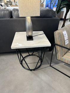 a table with a lamp sitting on top of it next to a couch and chair