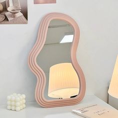 a table with a lamp and a mirror on it, next to a cell phone