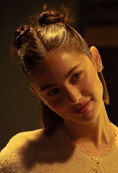 a young woman is smiling at the camera with her hair in a pony tail bun