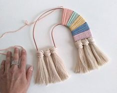 a hand holding a string with tassels attached to it on a white surface