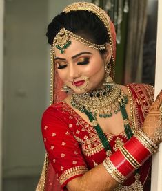 a woman in a red and gold bridal outfit is holding her hands on the wall