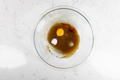 two eggs in a bowl on a white counter top with brown and yellow dyes