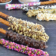 four different types of donuts with sprinkles and nuts on them sitting on a table