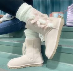 a pair of women's white boots with bows on them sitting on some steps