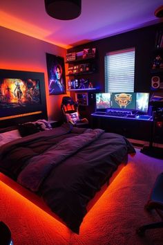 a bedroom with a bed, desk and two monitors on the wall above it is lit up by red lights