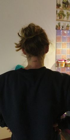 the back of a woman's head with her hair in a bun and tattoos