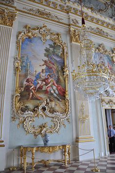 an ornately decorated room with chandelier and paintings on the wall behind it