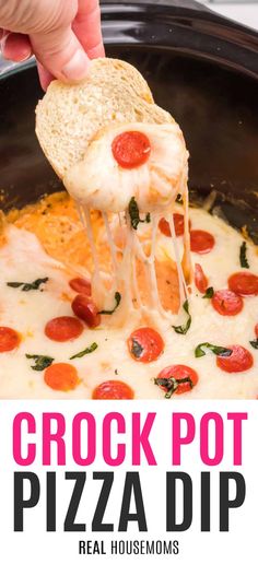 a hand holding a piece of bread over a pizza dip in a crock pot