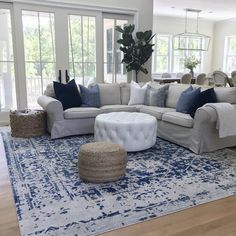 a living room with white couches and blue rugs on the hardwood flooring