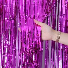 a woman's hand is reaching for the purple tinsel fringes that are hanging in front of her