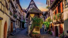 an old european street with cobblestone and half - timbered buildings at sunset