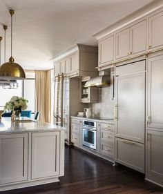 a large kitchen with white cabinets and silver appliances in the center, along with blue chairs