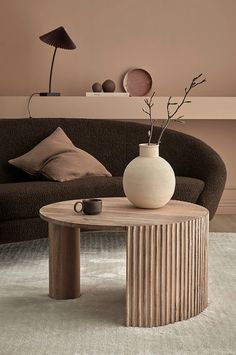 a living room with a couch, coffee table and vase on top of the table