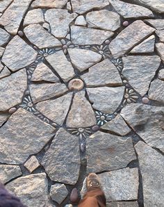 a person standing on top of a stone floor next to a circle pattern in the ground