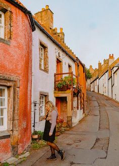 a woman is walking down the street in an old town