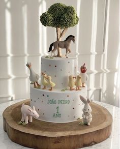 a three tiered cake decorated with farm animals and trees