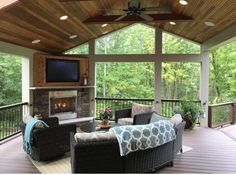 a covered porch with furniture and a flat screen tv on the wall, along with a fireplace