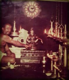 an old photo of a man sitting in front of a statue